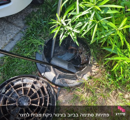 צינור מתכת בתוך פתח ביוב פתוח ליד מכסה